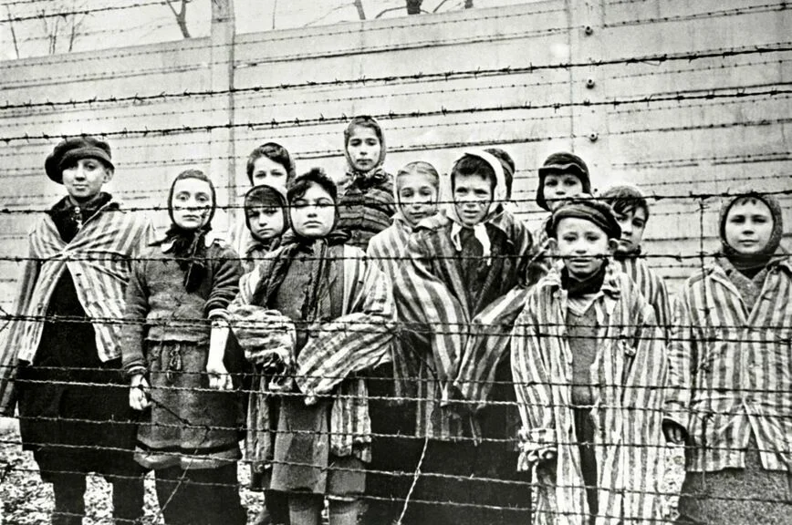 Февраль 1945 года. Выжившие в Освенциме еврейские дети за забором из колючей проволоки.
