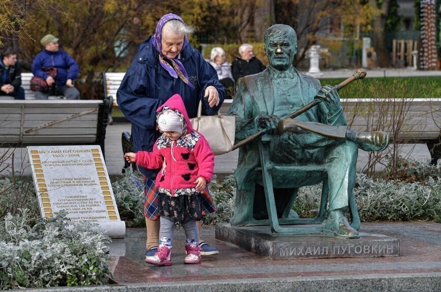 Люди во время отдыха у памятника актеру Михаилу Пуговкину на набережной в Ялте